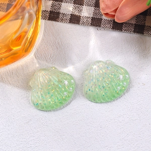Detailed macro shot of small green glitter resin starfish shell charms for DIY accessories