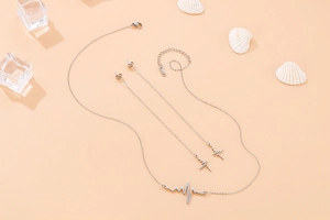 Macro shot of silver heartbeat necklace and long lightning earrings on creative summer background
