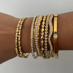 Dettaglio di bracciali rigidi dorati a strati con cristalli sul polso del modello