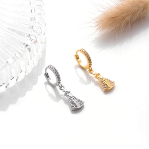 Detailed shot of gold and silver piercing earrings with religious pendants and zircons