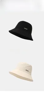 Detail view of foldable sun bucket hats in black and beige with brand label