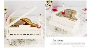 Detail of a white piano music box with rotating ballerina and gold mechanical gears