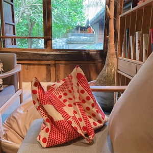Détail du sac cabas en toile à pois rouges posé sur un canapé au style vintage