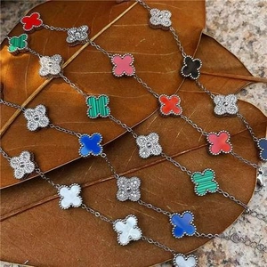 Close-up of colorful clover bracelets with inlaid stones on natural leaf backdrop