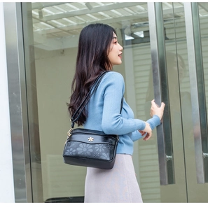 Detailed scene shot showing an elegant floral print black shoulder bag worn by a model.