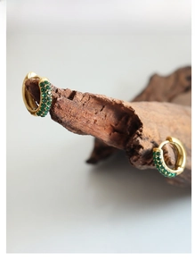 Detailed macro view of 18K gold plated hoop earrings with micro-pave green zircons