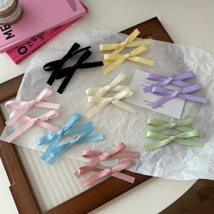 Set of eight colorful double-layer silk ribbon bow hair clips on aesthetic background