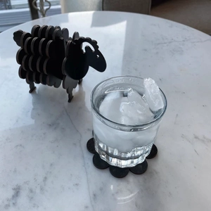Macro shot of black wooden sheep coasters used for glass cup on marble table