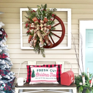 Couronne de Noël rustique sur roue de charrette avec pommes de pin dans un décor festif.