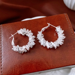 Gros plan de boucles d'oreilles géométriques argentées serties de cristaux scintillants