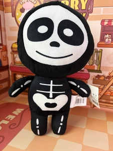 Close-up of Halloween plush skeleton toy showing detailed stitching and product tag