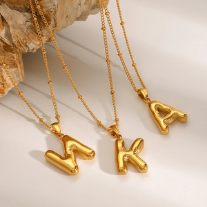 Macro shot of gold balloon-style initial pendants W, K, A on polished bead chains