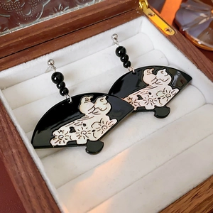 Detail of oriental style black fan earrings with bird and flower motifs in a wooden box