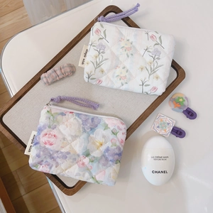 Close-up of floral quilted cotton pouches featuring small flower patterns and purple zippers