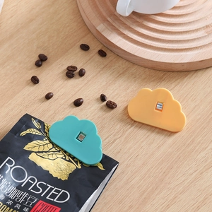 Cloud-shaped kitchen food sealing clips in cyan and orange on a coffee bean bag