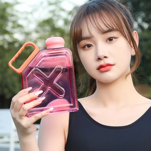 Outdoor view of large pink transparent plastic sports bottle with orange handle and lid