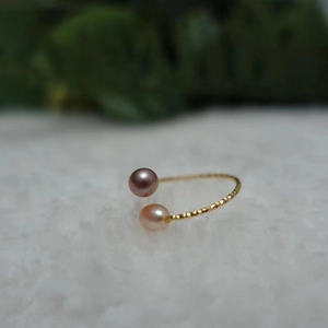 Elegant adjustable gold ring with pink and purple freshwater pearls on white plush surface