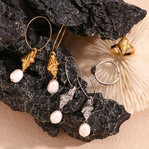 Detail of 18K gold and silver plated conch shell earrings with freshwater pearls on coral