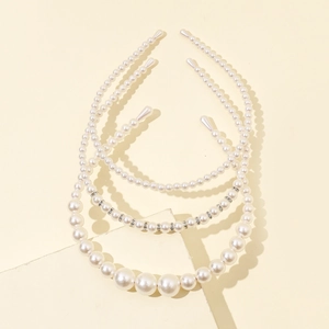 Detailed close-up of three pearl headbands with different bead sizes on stone props