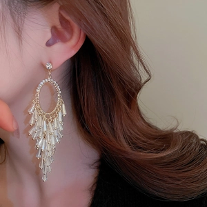 Close-up of golden tassel earrings with sparkling crystals worn by a female model