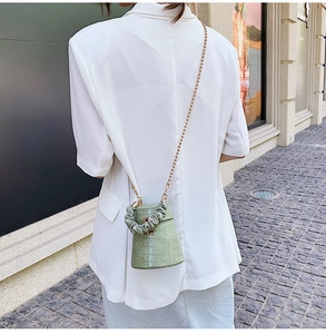 Light green crocodile pattern bucket bag with pleated handle and gold chain on street