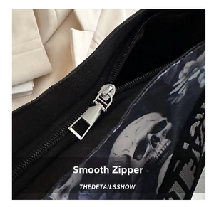 Detailed close-up of smooth silver metal zipper and skull print on nylon crossbody bag