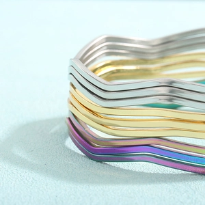 Nahaufnahme der gedrehten Edelstahl-Armreifen in poliertem Silber, Gold und Regenbogenfarben