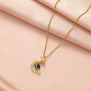 Detail of gold moon and star pendant necklace on pink silk fabric with blue stone