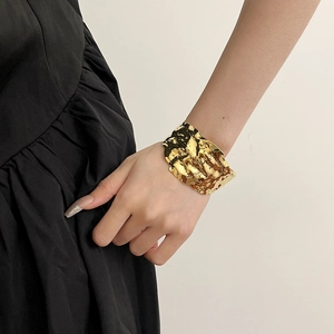 Polished gold wide cuff bracelet with irregular wrinkled texture in C-shaped open design
