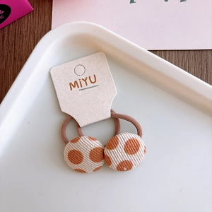 Detalle de gomas para el pelo con flores en color beige y marrón con textura de pana suave
