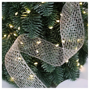 Close-up of silver mesh ribbon with warm LED lights on a Christmas tree branch