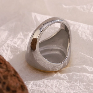 Detail shot of a minimalist 18K gold and silver two-tone wide band ring on textured paper