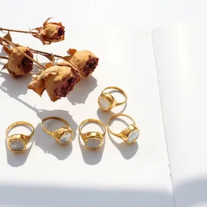 Close-up of gold-plated rings with white shell inlays and hammered texture on paper