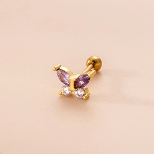 Orecchino a farfalla dorato con zircone viola e chiusura a vite su sfondo rosa pastello