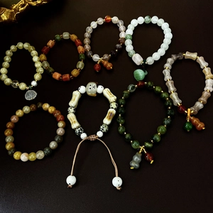 Flat lay of Chinese style beaded bracelets with lotus and gourd pendants on dark leather