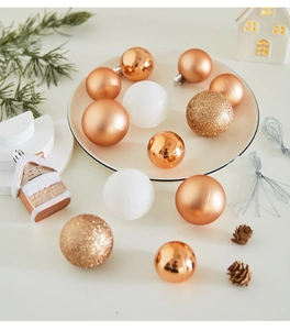 Close-up of rose gold and white Christmas balls with glitter textures and snowy house decor