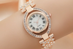 Primo piano di un orologio al quarzo dorato con strass e quadrante in madreperla