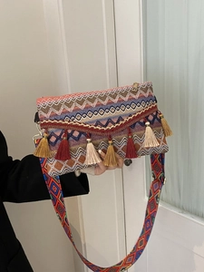 Detailed close-up of bohemian handbag with colorful woven textures and tassel charms