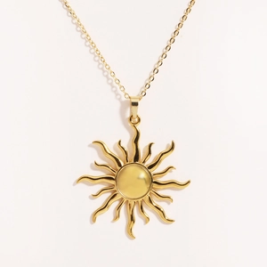 Dettaglio macro della collana con ciondolo a sole in acciaio dorato su sfondo bianco