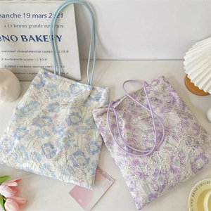Close-up of floral canvas tote bags with delicate white lace overlay and soft handles