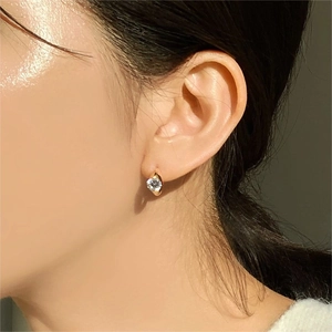 Close-up of minimalist gold cubic zirconia stud earring worn on a model's ear