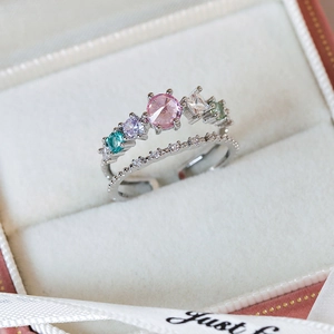 Macro shot of double-layered silver ring with colorful zircons on a beige velvet box