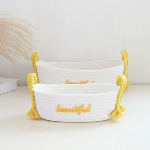 Detail of white cotton rope baskets with yellow tassel handles and beautiful embroidery