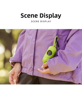Green pill-shaped dog poop bag dispenser with hook attached to a jacket pocket for walking