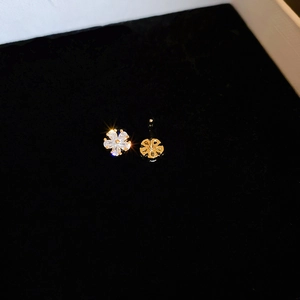 Vue détaillée des boucles d'oreilles fleur dorées avec zircons sur fond de velours noir