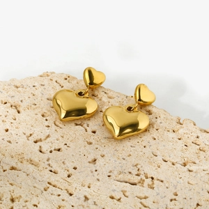 Detailed view of 14k gold-plated double heart earrings on natural travertine stone