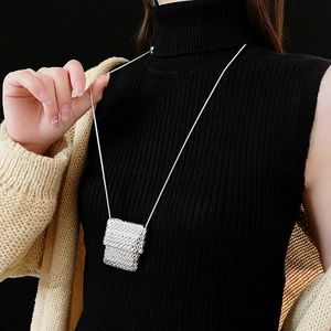 Detail of a silver metal woven mini bag necklace on model with black background