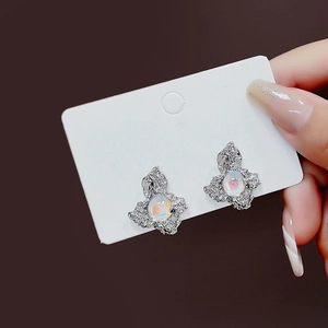 Macro detail of irregular silver earrings featuring iridescent opals on a display card