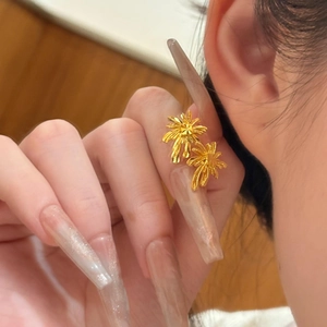 Close-up of gold palm tree stud earrings worn by a model with a minimalist background