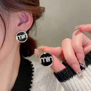 Elegant round black enamel stud earrings with crystal letter inlay and gold finish